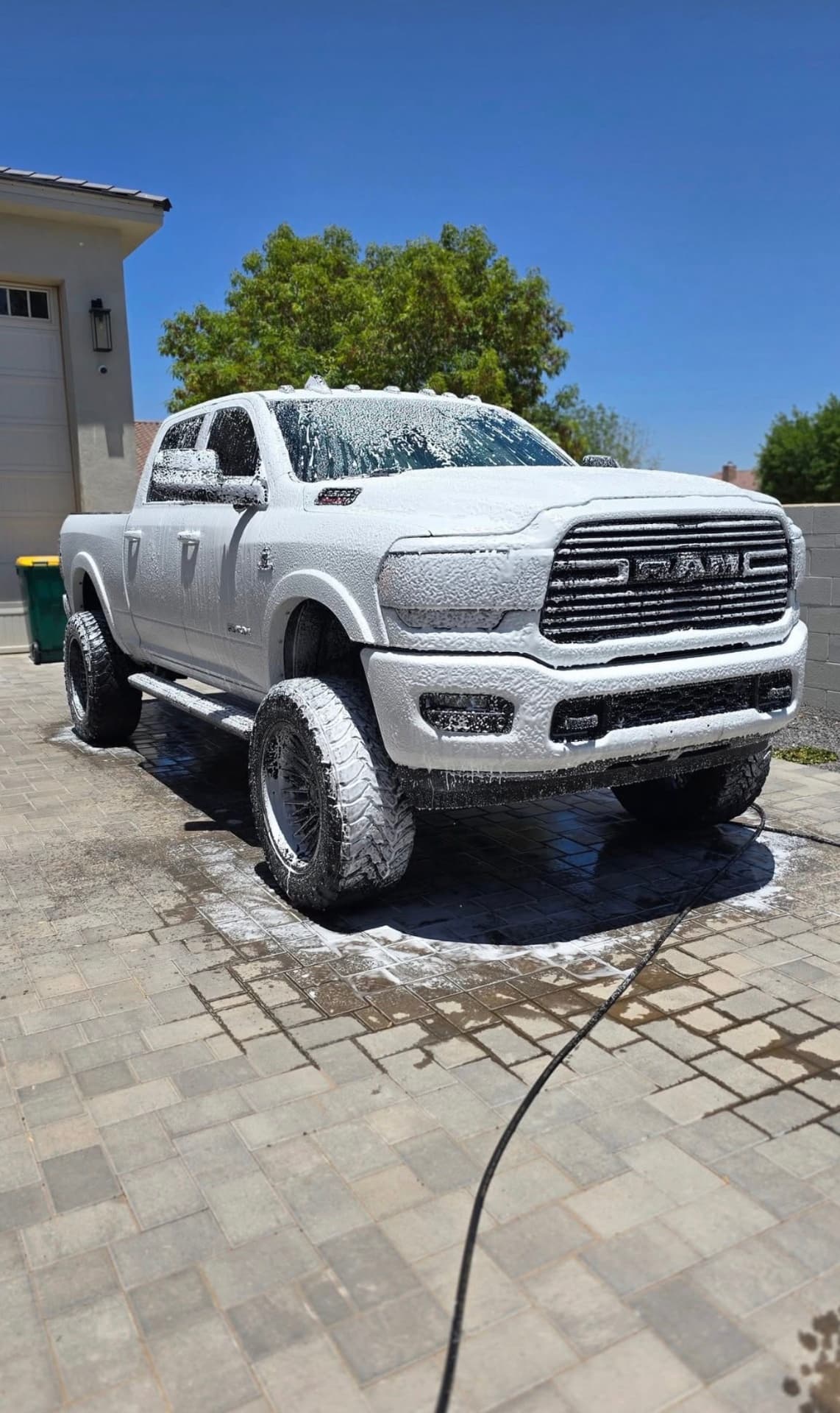 Lifted white RAM truck covered in thick foam during a SteelShine hand wash